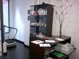 Consultorio estético con vitrinas de productos de belleza, impresora y máquina de ejercicio.