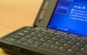 Nahaufnahme eines geöffneten, kleinen Laptops mit Tastatur und blauem Bildschirm.