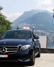 Schwarzes Taxi an malerischem Ort mit Bergen, Palmen und Natur im Hintergrund.