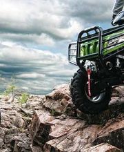 Dos personas manejan vehículos todoterreno sobre rocas bajo un cielo nublado.