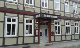 Hotel Am Glockenturm mit Fachwerkfassade und großen Fenstern an einer belebten Straße.